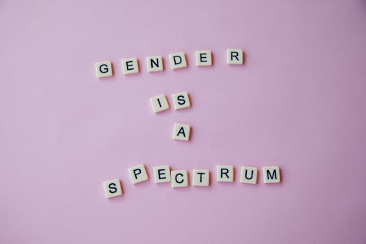 From above of composition made of letters with inscription Gender is a spectrum placed on pink background in studio